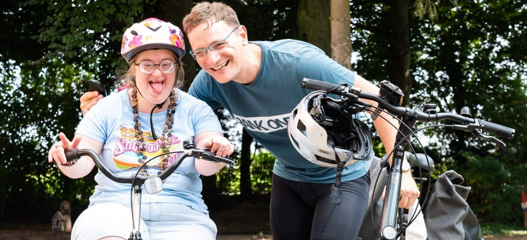 Woman with Down syndrome and her brother riding bikes in a park